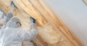 FortisBC providing renovators twice the reason to invest in energy savings Professional workman in protective uniform installing thermal insulation layer under the roof.