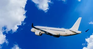 Canadians Cut Daily Expenses to Fund 2024 Travel Plans Passengers Commercial airplane flying above dramatic clouds